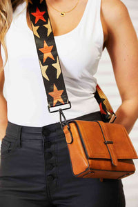Close-up of a woman wearing a wide strap crossbody bag with a stylish star-patterned strap.